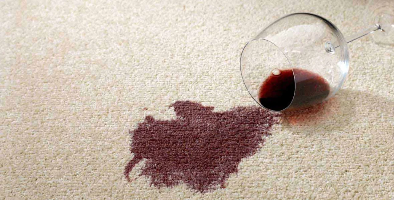 A red wine spill and tipped-over glass staining a light carpet