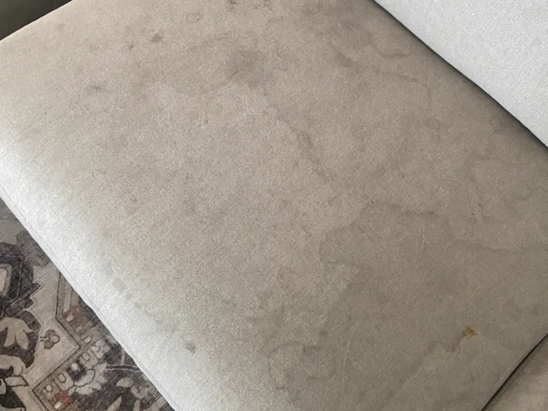 Upholstered sofa cushion with heavy soiling before cleaning